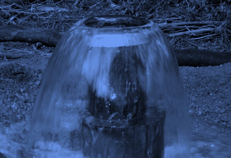 Moody blue groundwater block environmentally clean water spilling from ground pipe